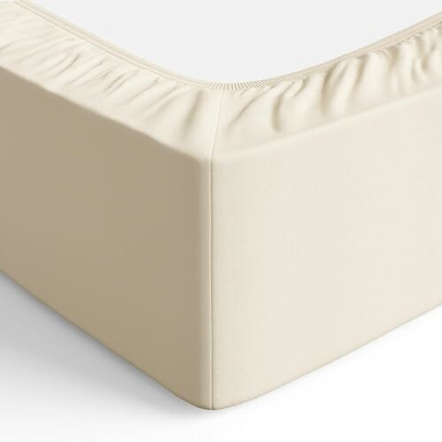 Drap-housse beige ajusté sur un matelas.