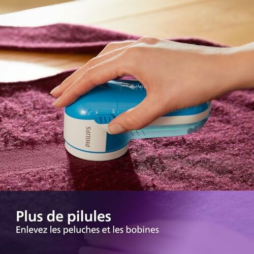 Main utilisant un rasoir anti-bouloches sur un tapis.