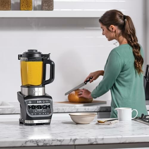 Femme utilisant un mixeur dans la cuisine.