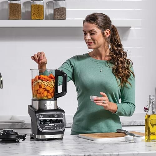 Femme utilisant un mixeur dans une cuisine moderne.